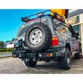 Gray rockarmor steel dual wheel carrier mounted on the rear of a toyota landcruiser fj105 off-road vehicle
